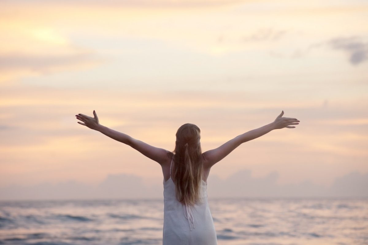 Woman at the beach with arms extended.